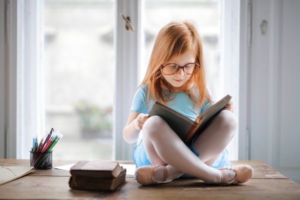 child reading a book and wearing glasses