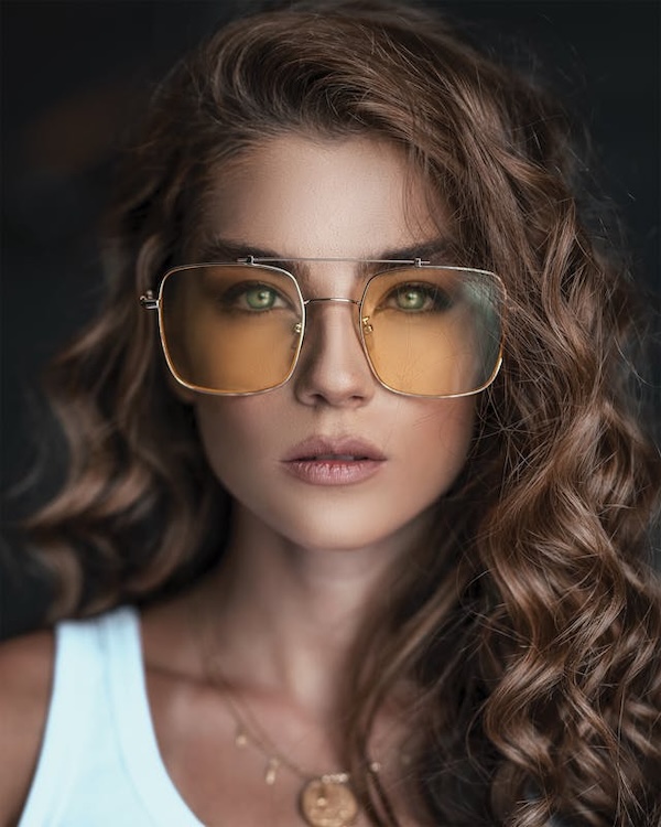 young girl in white tank top wearing large glasses